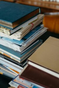 Close-up of a stack of various hardcover and softcover books on a table.